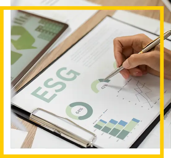 A person points at a chart on a clipboard with ESG written on it, surrounded by graphs, pie charts, and documents on a desk.